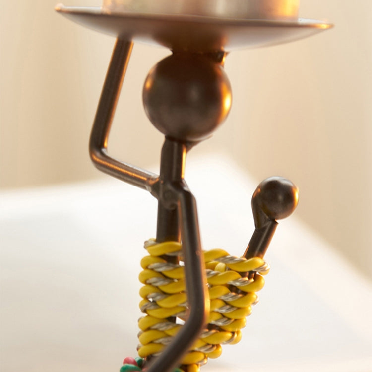 Close-up of metal candlestick ornament torso with yellow coiled spring and tray