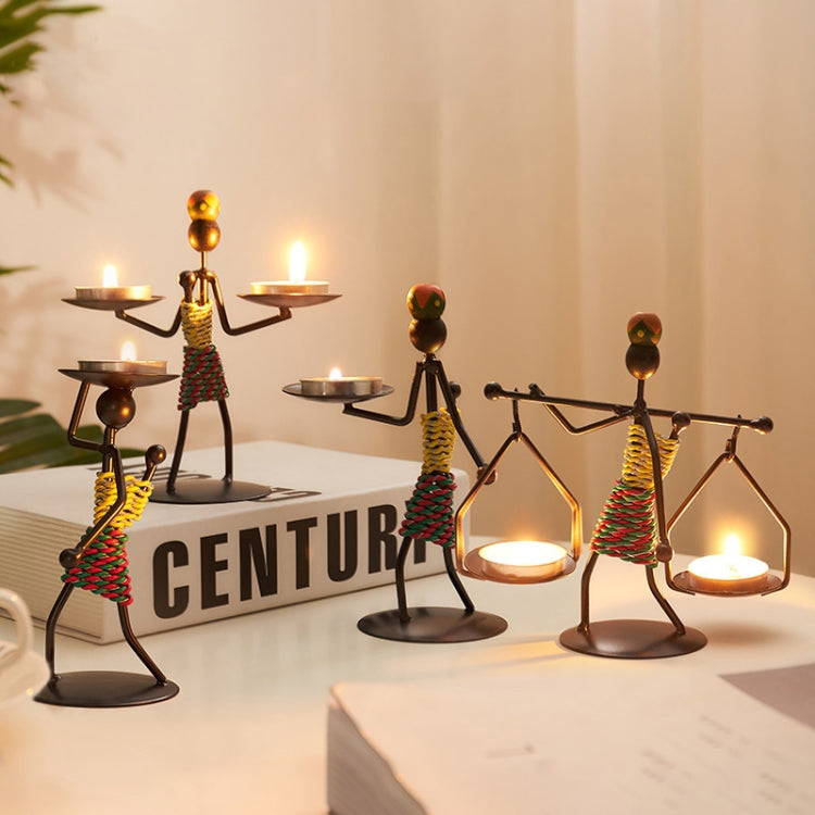 Group of man-shaped metal candlestick ornaments with lit candles and colorful coiled bodies