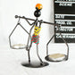 Man-shaped metal candlestick ornament with arms holding trays and colorful coiled body