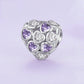 Heart-shaped silver bracelet bead with purple and clear zirconia stones in a cluster design
