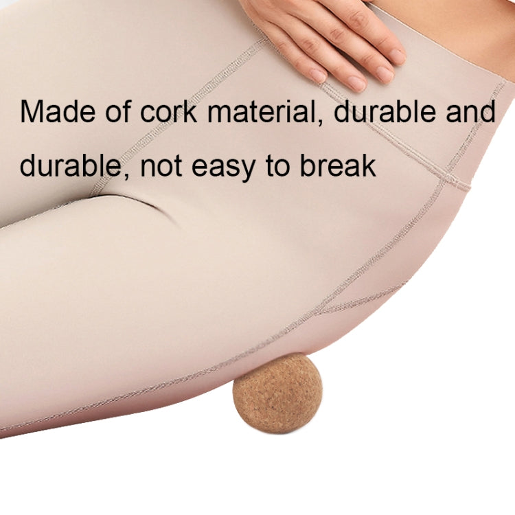 Cork massage ball under the leg during stretching on a mat.