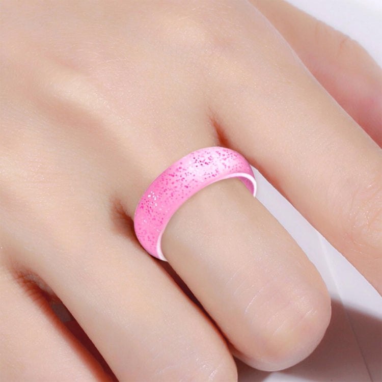 Pink glitter silicone ring, wide band, worn on finger.