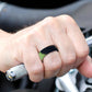 Curved black silicone sports ring with green inner band on fingertip