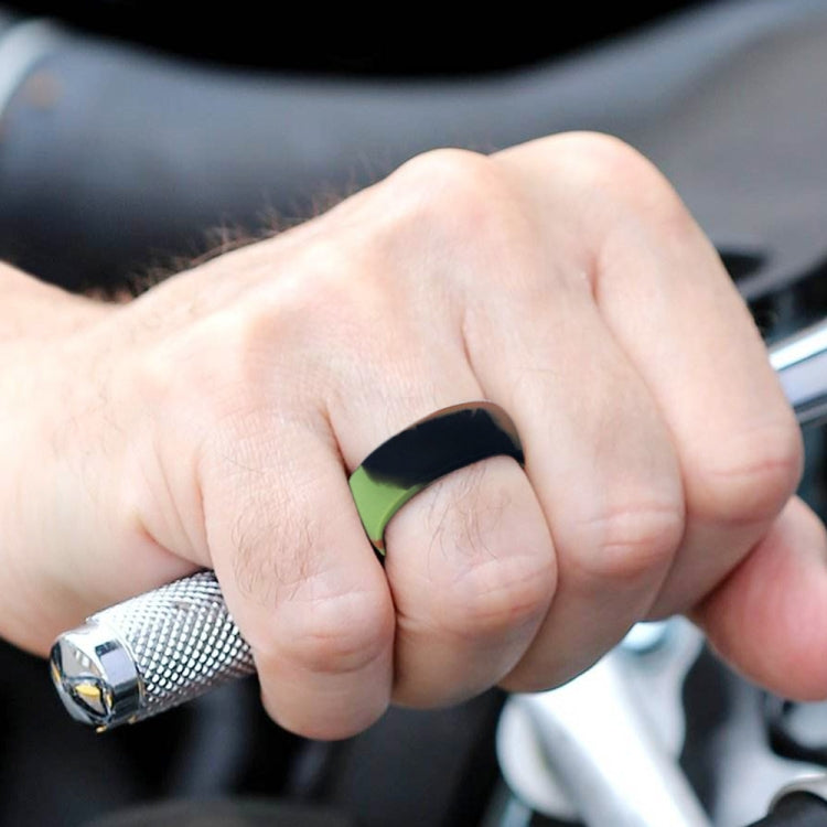 Curved black silicone sports ring with green inner band on fingertip