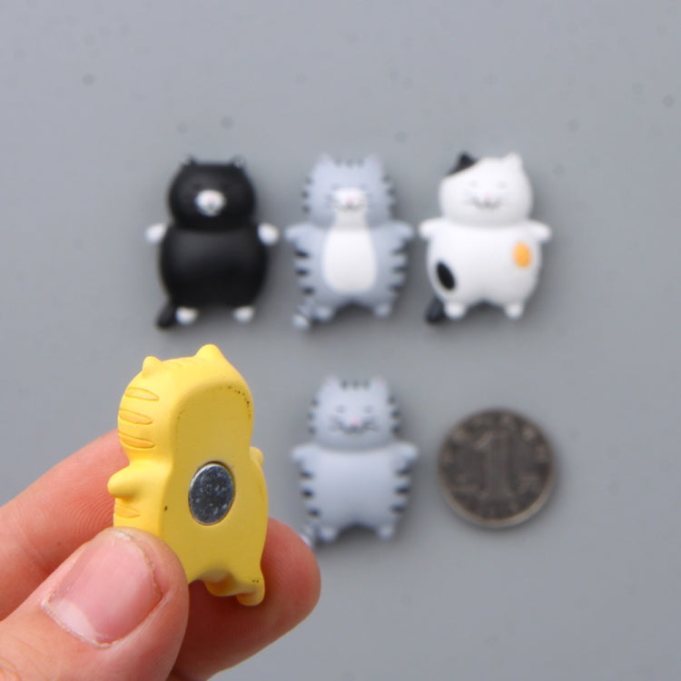 Assorted small 3D cat magnet stickers on a surface, including black and yellow