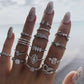 Multiple silver-tone rings on fingers with heart and water-drop gemstone charms