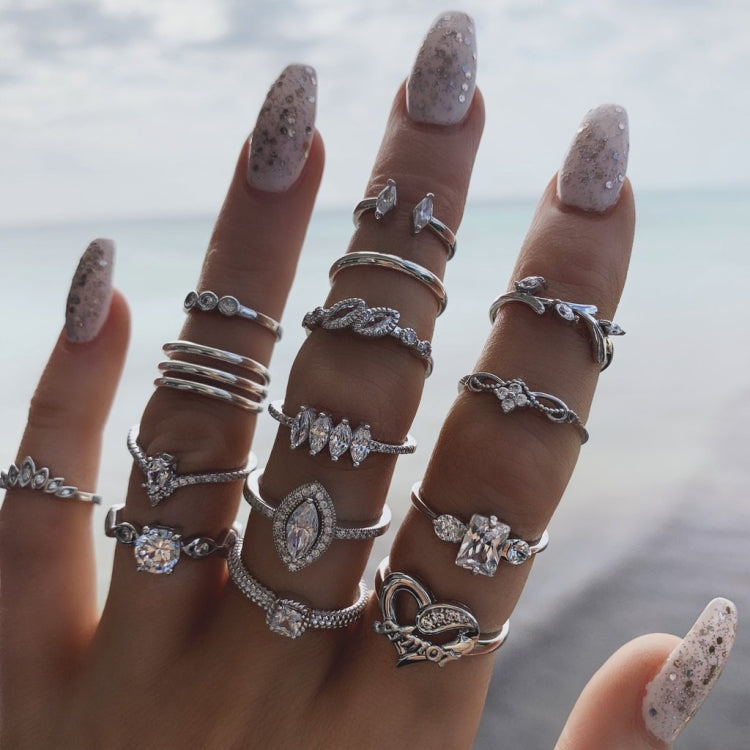 Multiple silver-tone rings on fingers with heart and water-drop gemstone charms