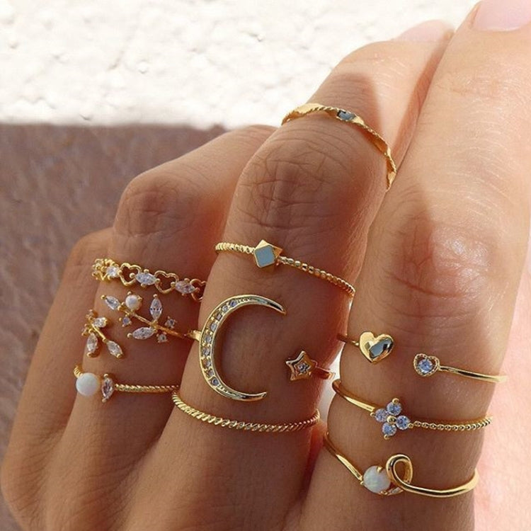 Gold-tone knuckle ring set on hand with rhinestone moon, star, leaves, heart accents