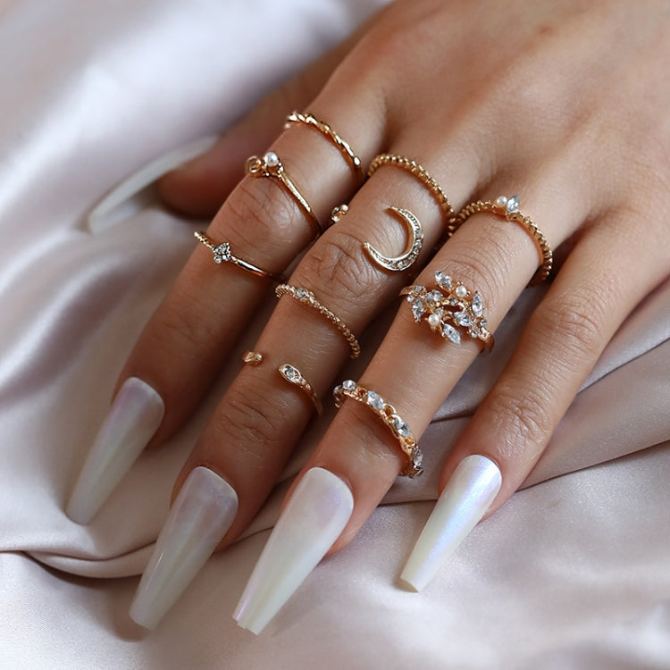 Close-up of gold-tone knuckle rings on hand with rhinestone crescent and heart stones