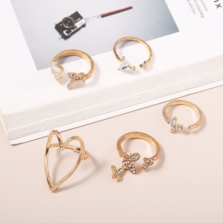 Gold-tone knuckle rings on display: heart, cross, and butterfly designs with stones