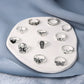 12-piece open ring set laid on tray, featuring heart, cross, butterfly, and spider designs