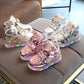 Assorted kids luminous sneakers on couch: silver and pink pairs with star print and LED soles