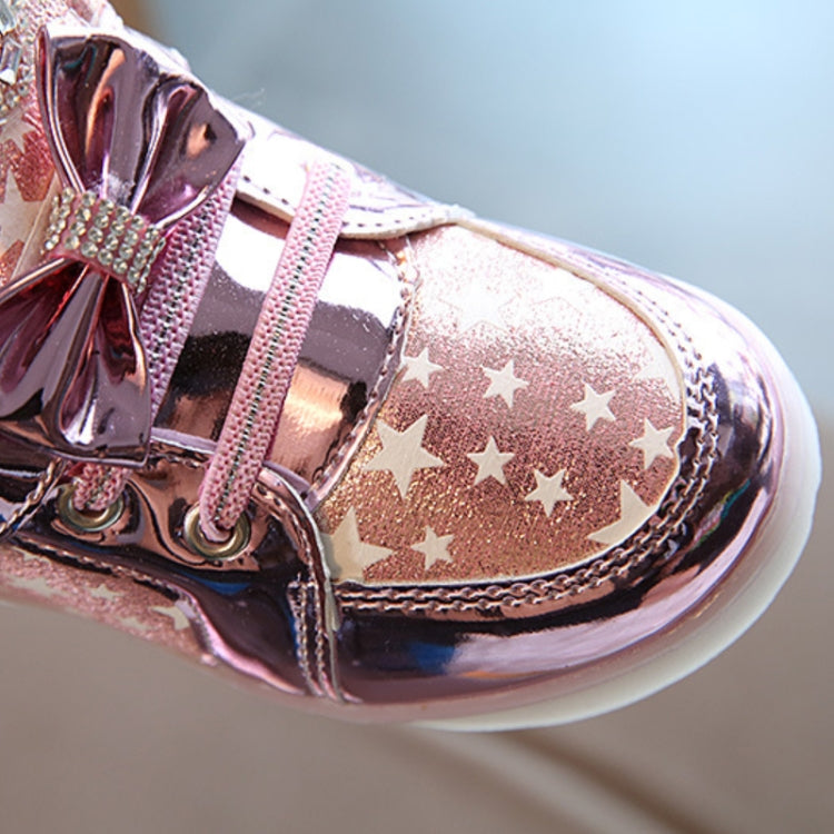 Pink metallic kids sneakers close-up, star print side panel with bow and LED sole light