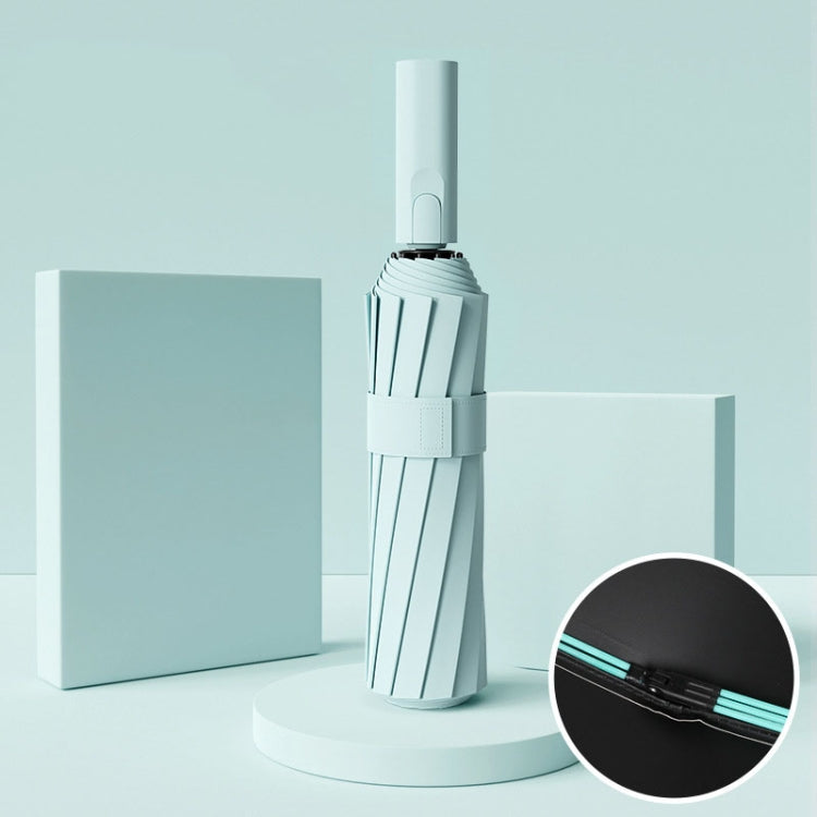 Mint green automatic umbrella, closed with strap and button handle