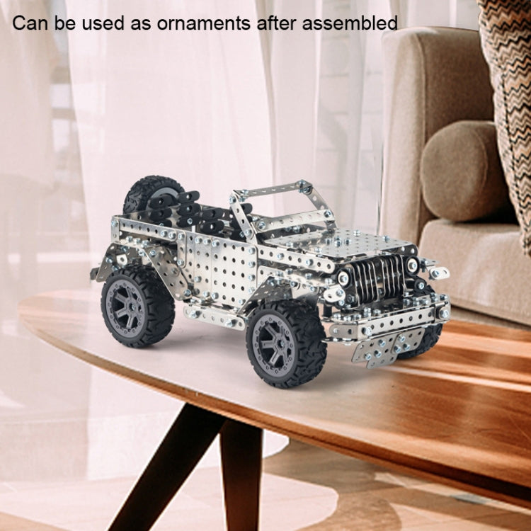 Metal off-road vehicle model toy with silver frame and black tires, standing on a display surface