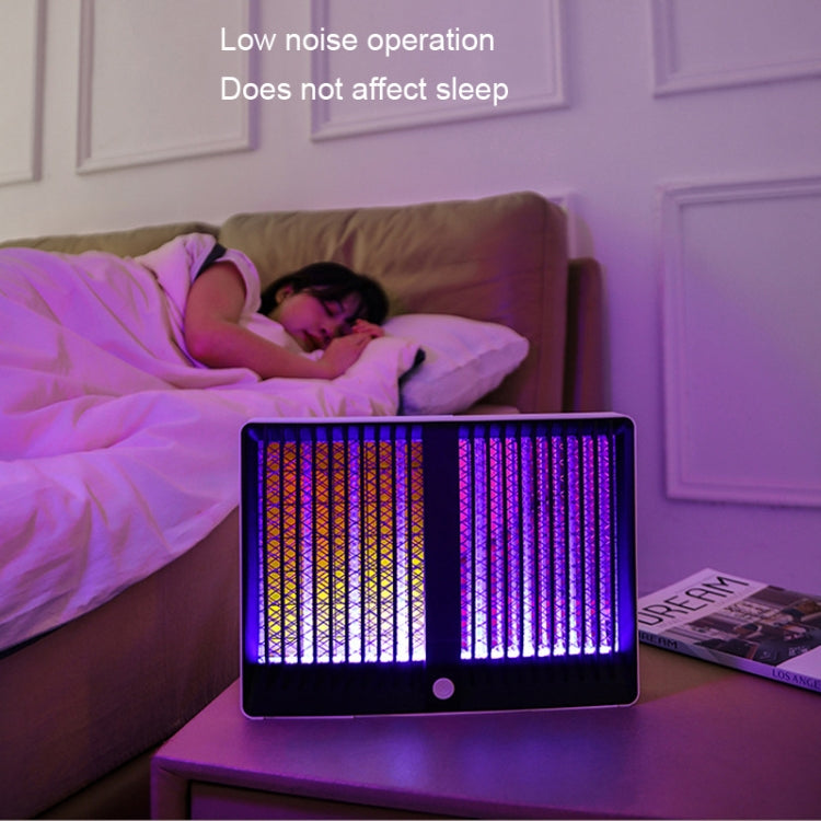 Black plug-in mosquito killer lamp on bedside table, purple UV light glow