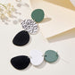 Long dangle earrings: teal circles with white leaf-print and black oval drops