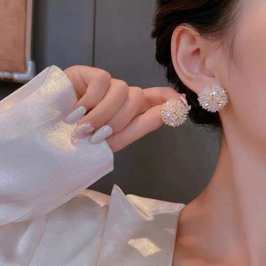 Pink crystal domed flower stud earrings on ear, gold-tone backings.