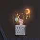 Warm orange crescent moon and astronaut glow stickers on a light switch cover