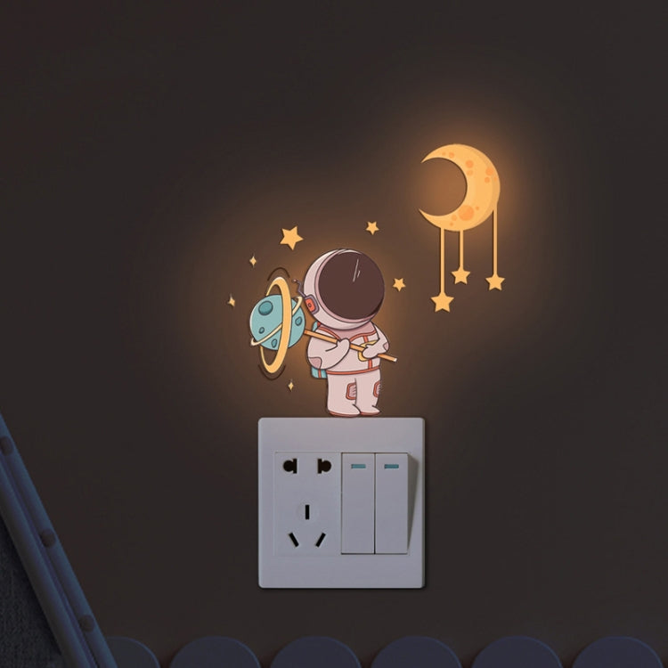 Warm orange crescent moon and astronaut glow stickers on a light switch cover