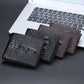 Men’s crocodile-print short wallets stacked together in dark tones.