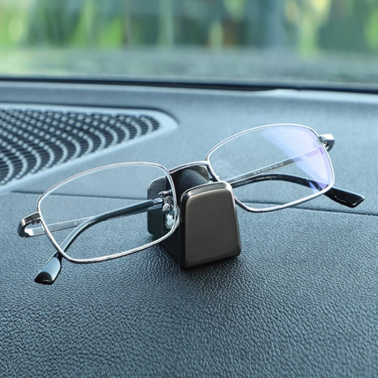 Car dashboard eyeglass holder with black case holding wire-framed glasses