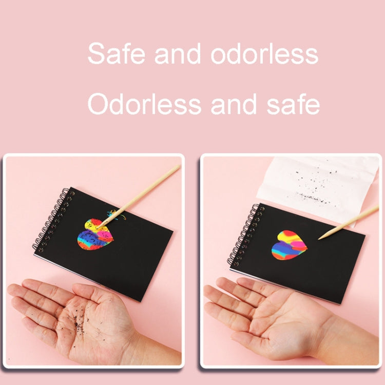 Scratch art notebook with wooden pencil on black page, hands shown using it