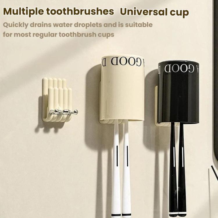 Toothbrush storage rack with cream and black cups and vertical toothbrush slots.