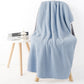 Light blue bath shower towel with waffle texture, draped over chair