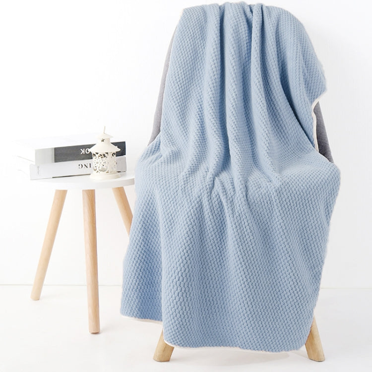Light blue bath shower towel with waffle texture, draped over chair