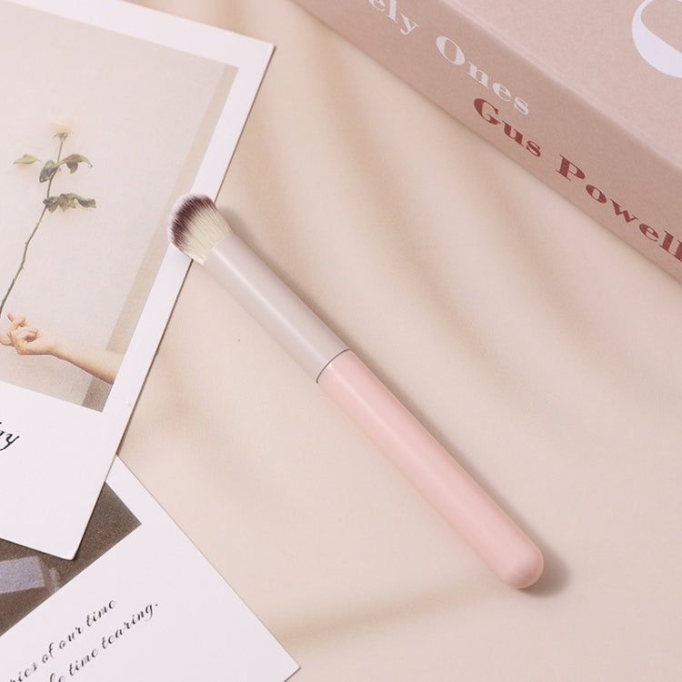 Angled concealer brush with rounded white head and pale pink handle