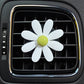 White daisy air vent aromatherapy clip with light yellow-green center, on car vent