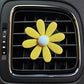 Yellow daisy air vent aromatherapy clip with light blue center, clipped to car vent