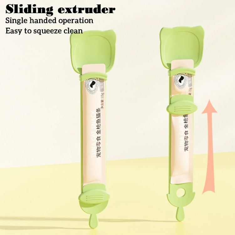 Green cat feeding spoon with sliding extruder for single-handed squeeze dispensing.