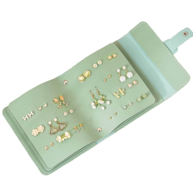 Green book-shaped jewelry bag with built-in earring slots and ring holders for travel
