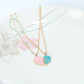 Gold-tone heart pendant necklace with pink and blue lock halves on layered chains
