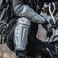 Motorcycle rider wearing white-and-gray knee and elbow pads with black straps and yellow accents
