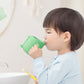 Dinosaur cartoon brushing cup with green finish, used by a child