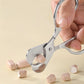 Stainless steel pill cutter scissors held in hand with rounded loop head and pink pieces