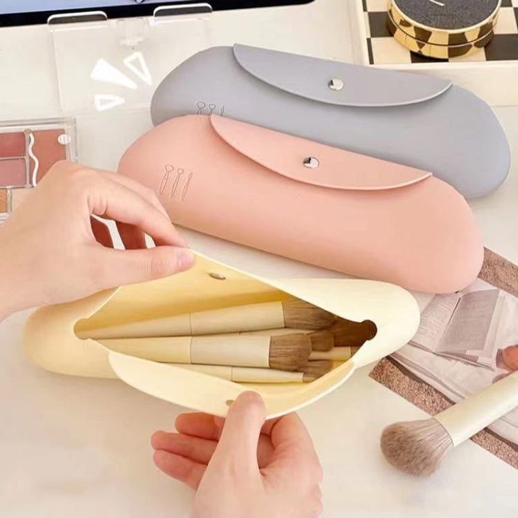 Pink silicone makeup brush storage bag open, holding makeup brushes and tools