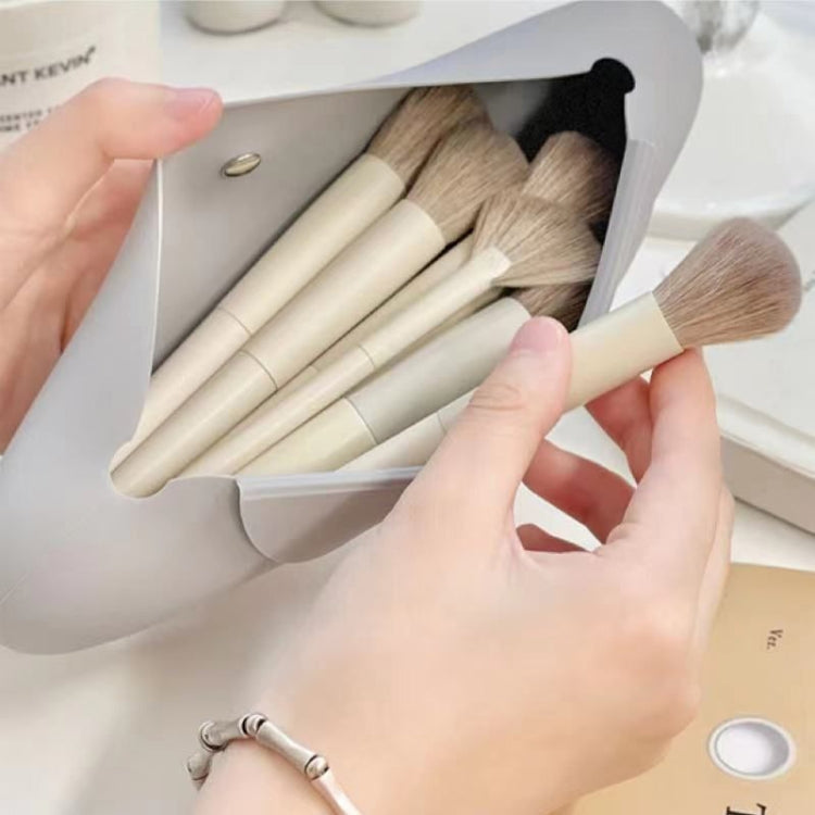 Gray silicone makeup brush storage bag open, holding multiple makeup brushes