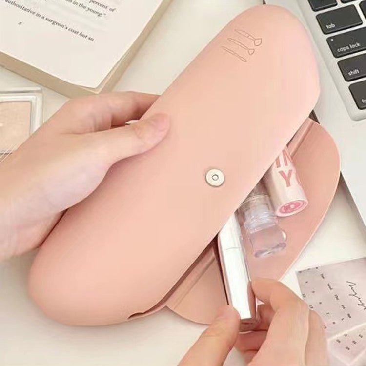 Pink silicone makeup brush storage bag open, showing brushes and beauty items inside
