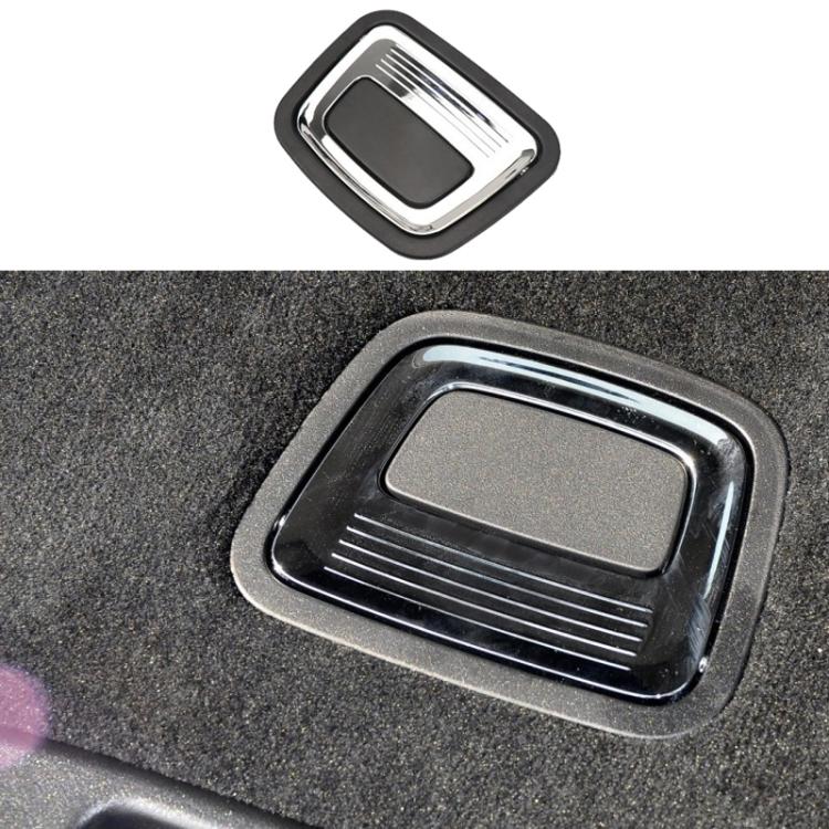 Black trunk inside puller switch with chrome frame, mounted on car carpet.