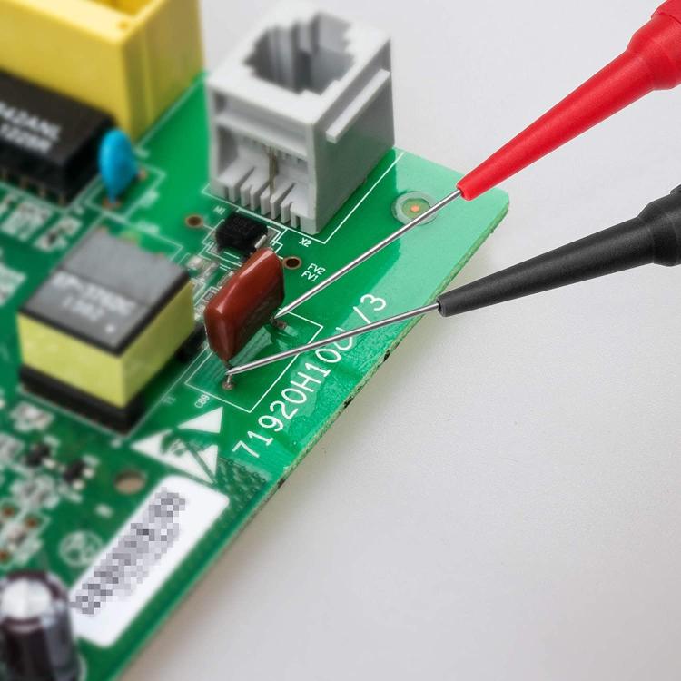 Red and black test probes touching a small circuit board
