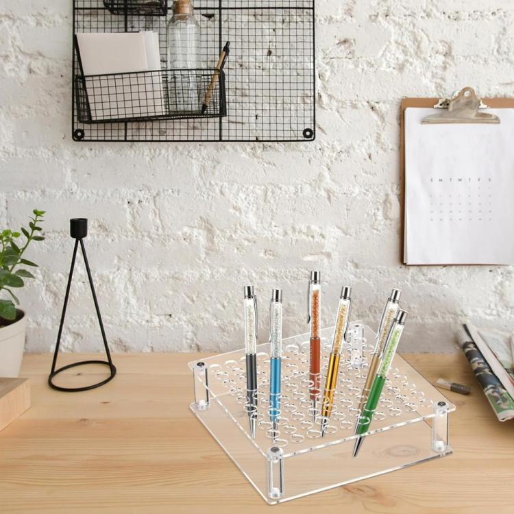 Clear acrylic pen and brush organizer on desk, holding pens in a single upright grid