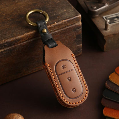 Brown genuine leather car key cover with black keyring and stitched oval button panel