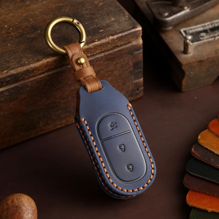 Blue genuine leather car key cover with tan strap, brass keyring, and stitched button icons