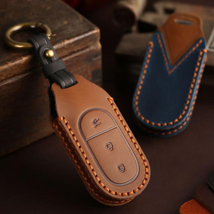 Brown genuine leather car key cover with black strap, brass ring, and stitched oval buttons