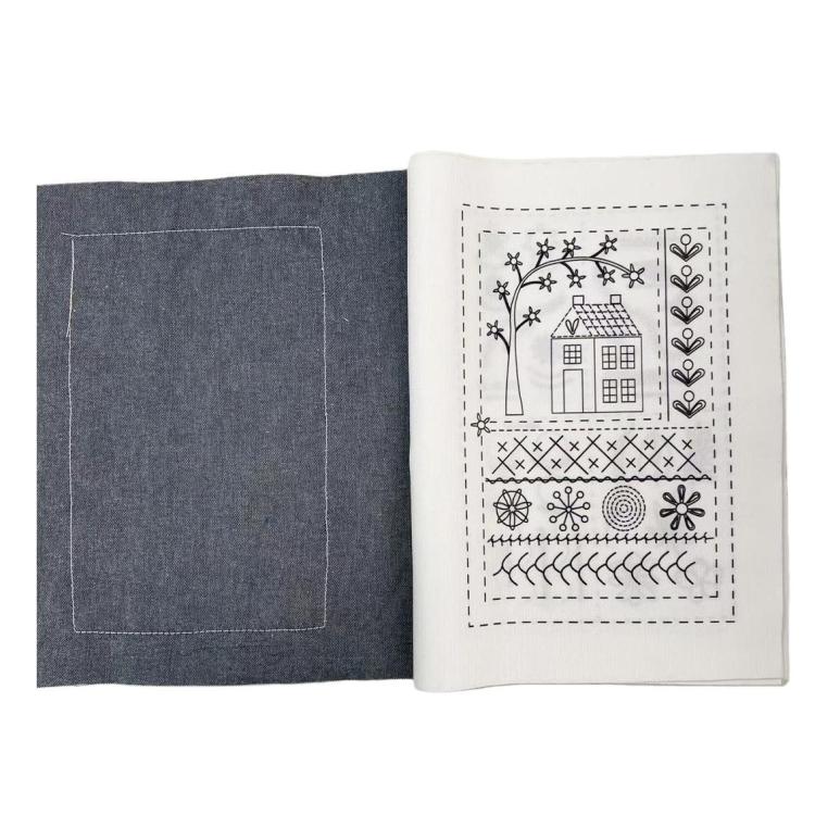 Open embroidery stitch book with dark cover and stitched motif on cream page