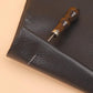Leather repair awl inserted into dark leather with wooden handle and steel needle